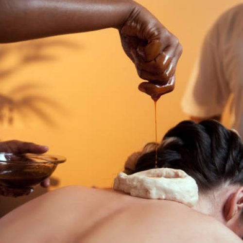 Two Indian massage therapist doing a Ayurveda massage with aromatic oils.